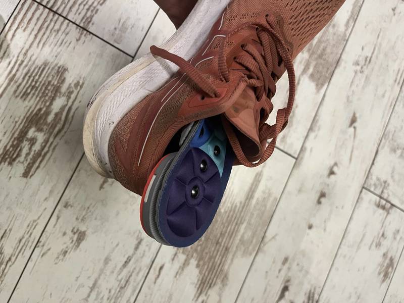 Akusoli acupressure insole placed inside a running shoe on a wood floor