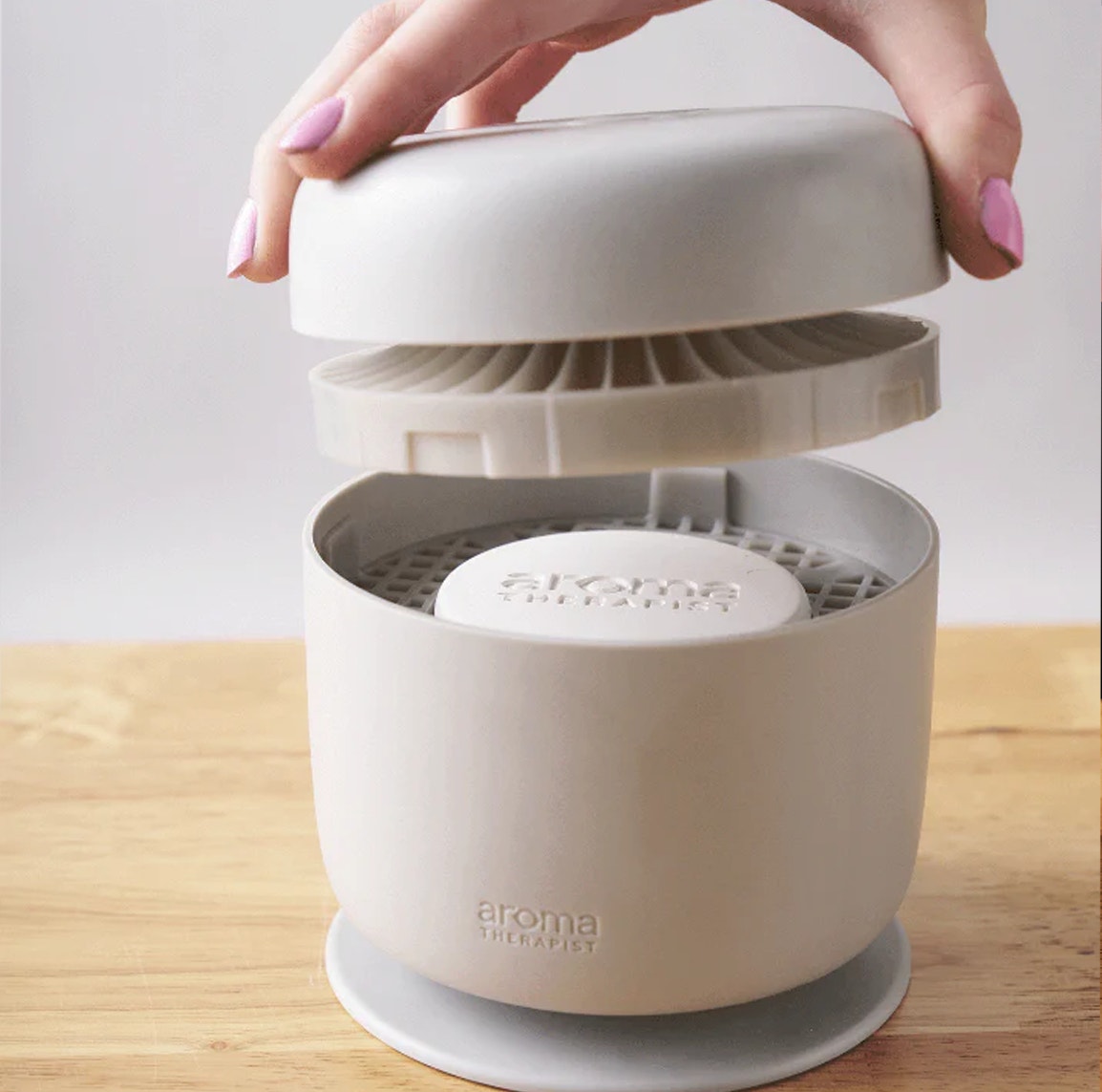 Aroma Amplifier waterless diffuser opened to show the fan grille and AromaPuck compartment