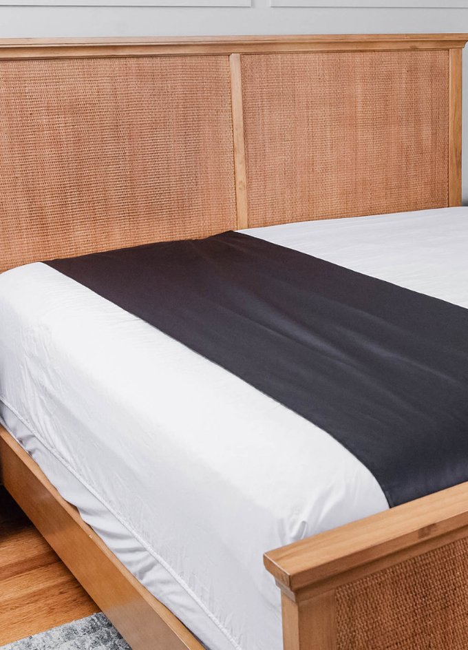 Earthing grounding sheet in charcoal draped across a made bed