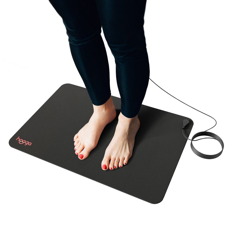 Person standing barefoot on a black Hooga grounding mat with the connecting cord attached