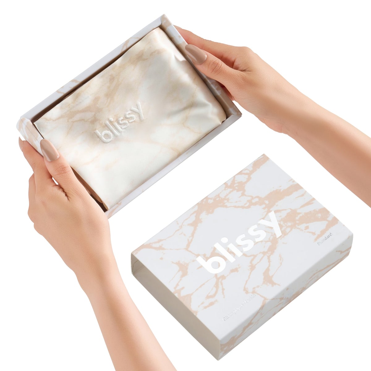 Hands opening a Blissy champagne marble silk pillowcase in its gift box