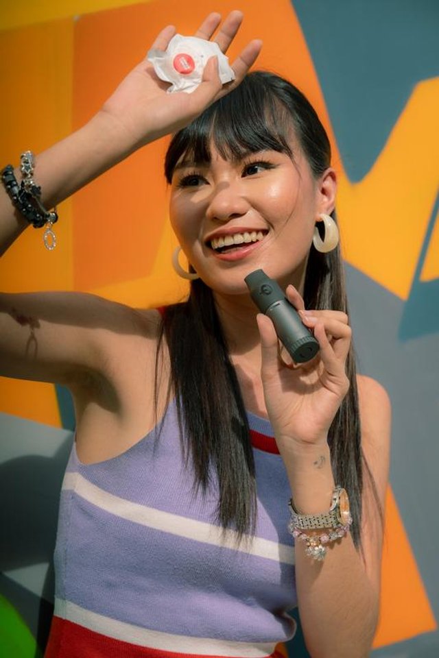 A person holding the Capnos Legura device and one of its round flavor pods
