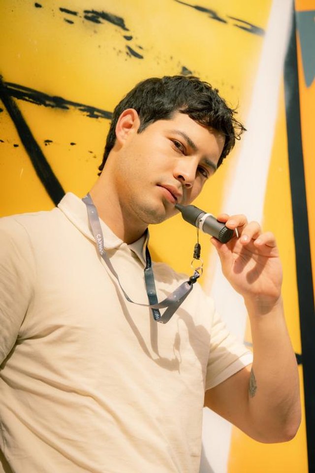 A person holding the Capnos Legura flavored-air device on its lanyard