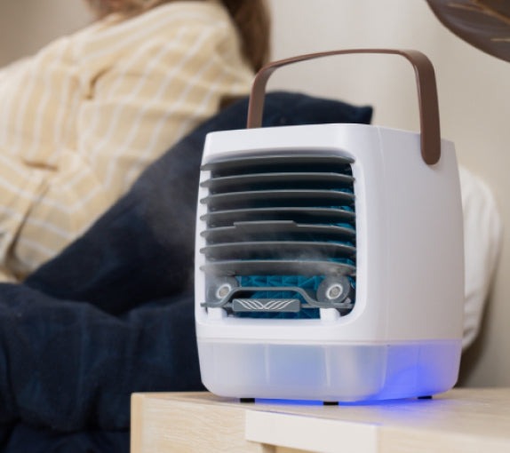 ChillWell 2.0 personal cooler on a bedside table with its mist running and blue night light on