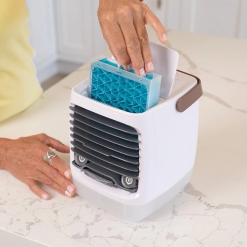 A hand sliding the blue cooling cartridge into the ChillWell 2.0 personal evaporative cooler