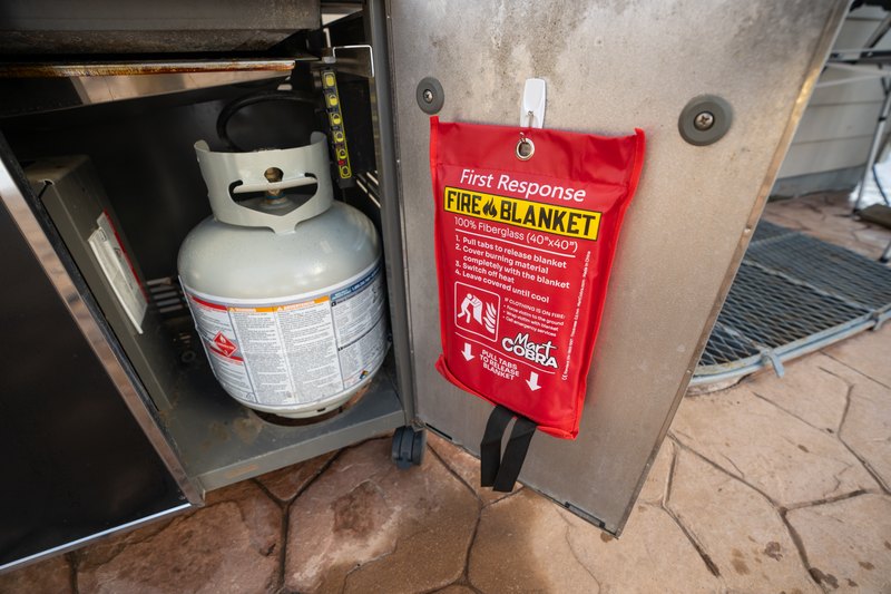 Cobra Fire Blanket pouch mounted on an outdoor grill station next to a propane tank