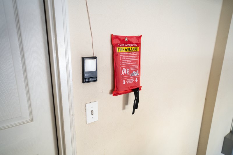 Cobra Fire Blanket pouch mounted on a hallway wall beside a smoke alarm and light switch