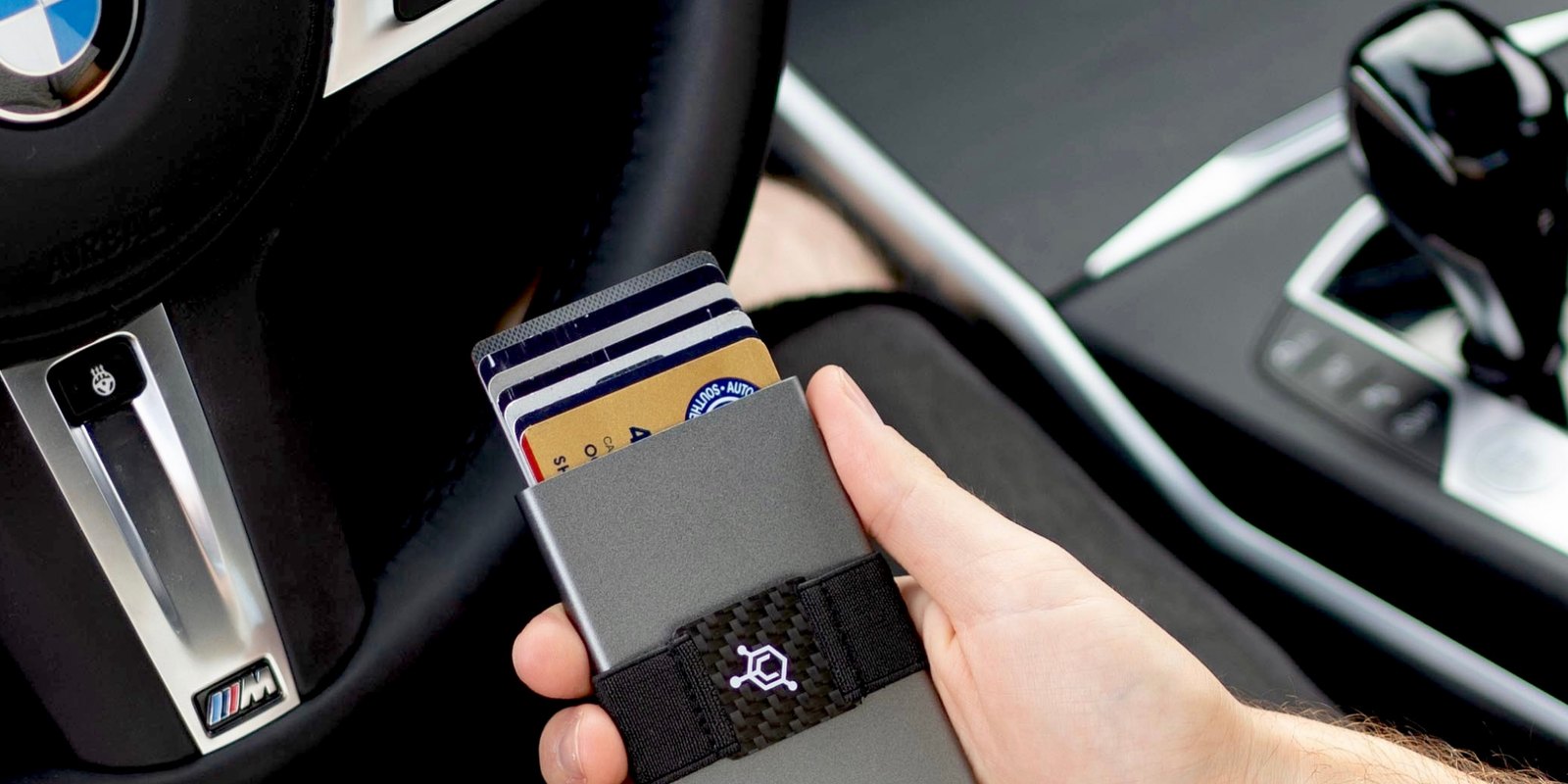 A person holding the Code 118 aluminum wallet with cards fanned out of the pop-up chamber