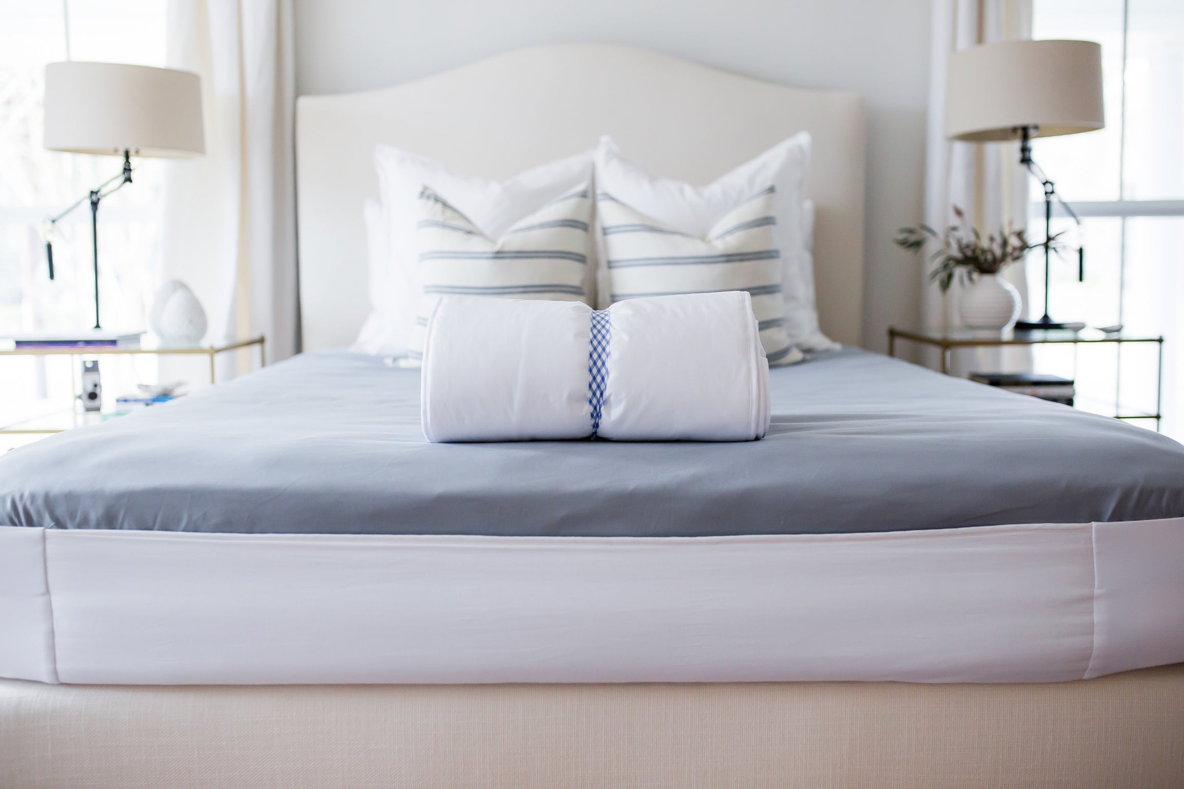 The white Better Bedder elastic band wrapped around a made mattress in a styled bedroom