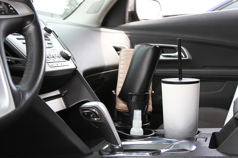 CupStation in a car console holding a tumbler with a spray bottle beside the gear shifter