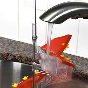 DNA Helix hummingbird feeder section being rinsed under a kitchen tap during cleaning