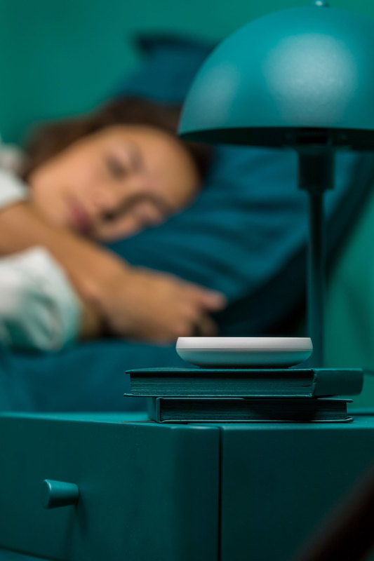 Dodow sleep light resting on a stack of books on a nightstand