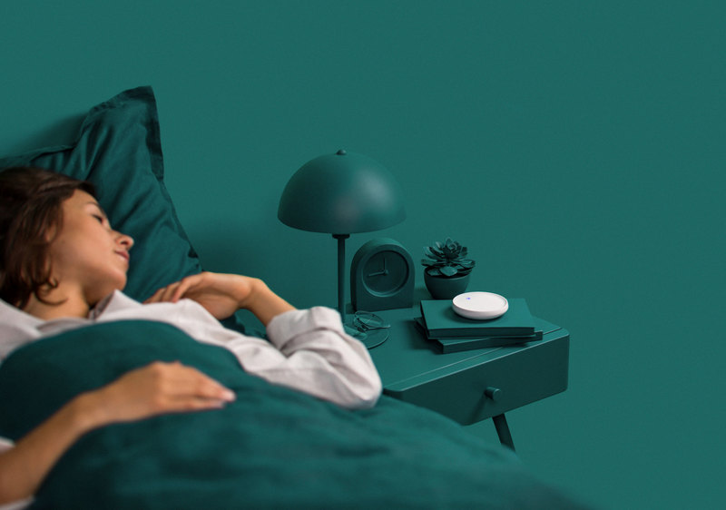 Dodow on a bedside table beside a person sleeping on their back