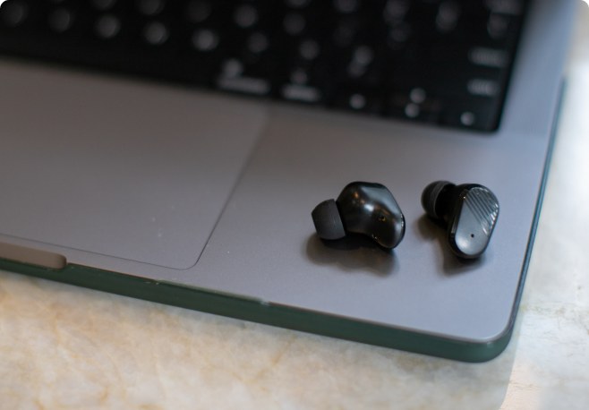 Two black Echo Labs earbuds resting on a laptop, showing the textured ridged finish on each bud