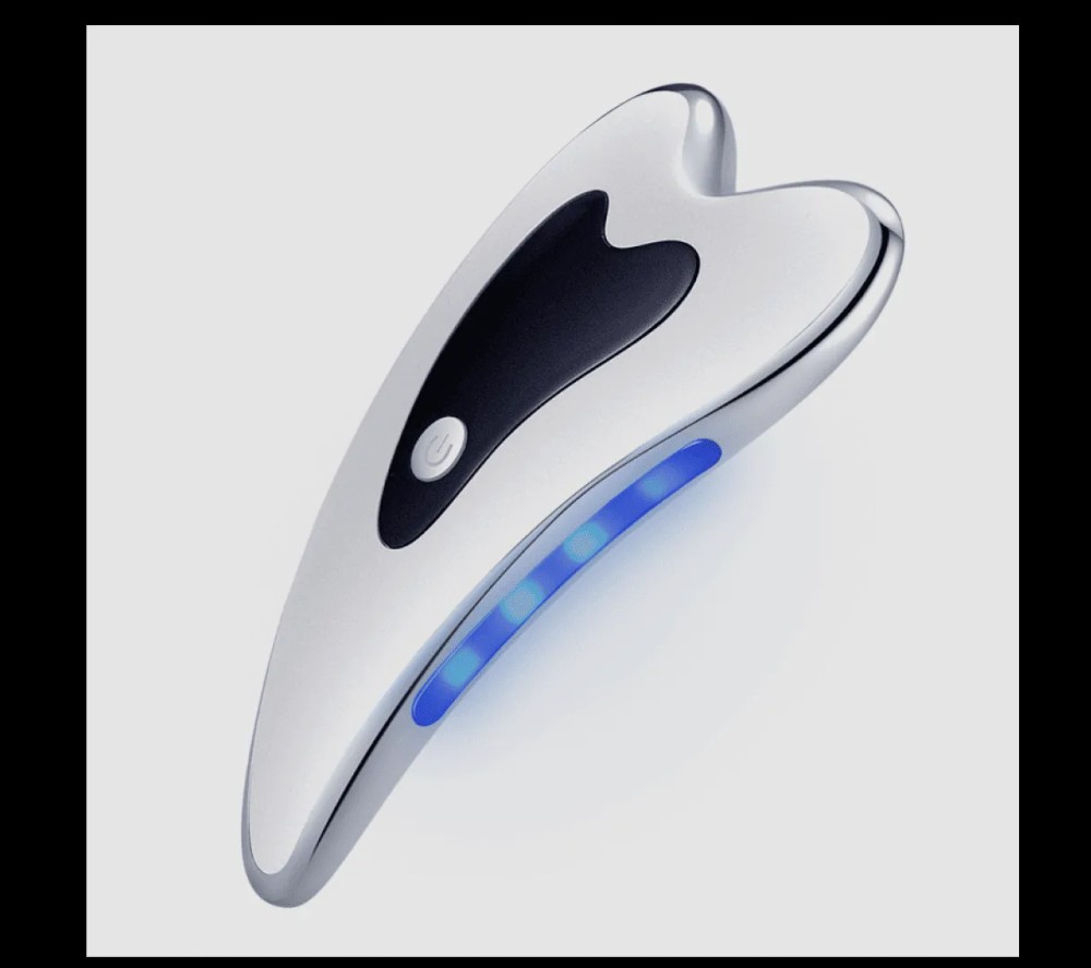 The Glokore electric gua sha facial tool with its blue light strip lit