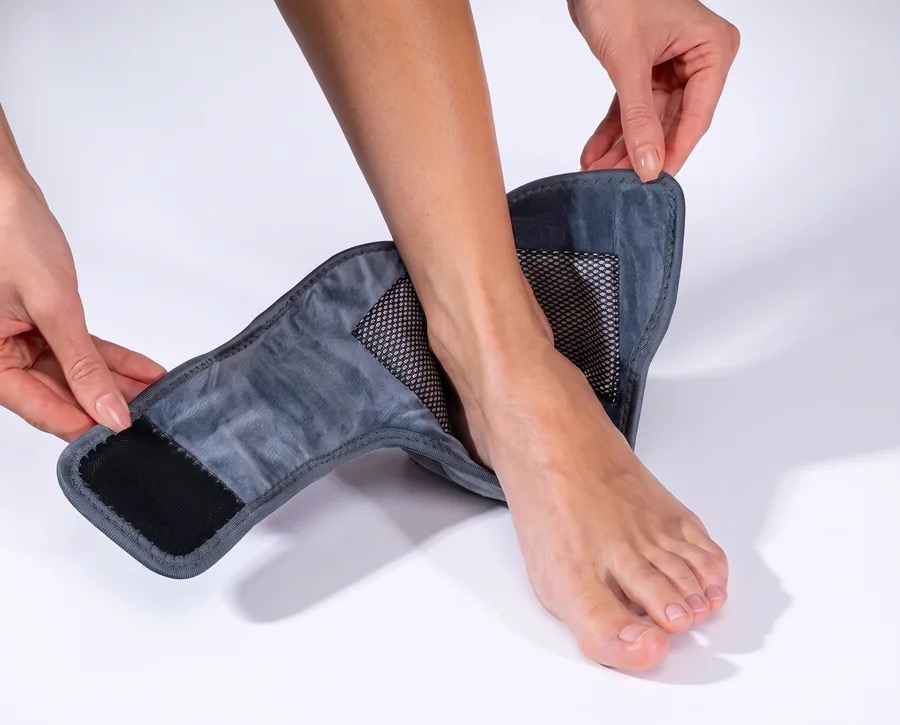 Opening the EMSense foot wrap to slip a bare foot inside, showing its grey fabric lining