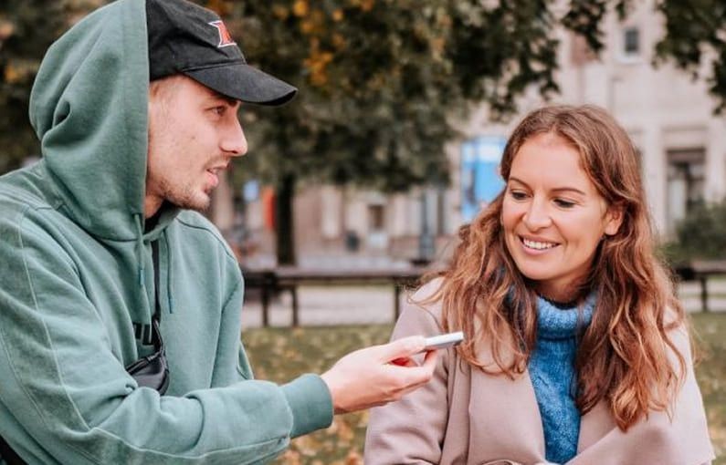 Two people having a conversation outdoors using the MUAMA Enence translator