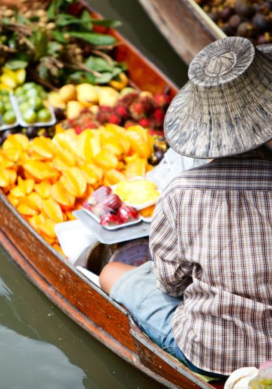 A vendor boat piled with fresh fruit at a floating market, a typical place to haggle in another language