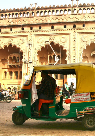 An auto-rickshaw outside a historic building in India, a place where a two-way translator helps with directions and fares