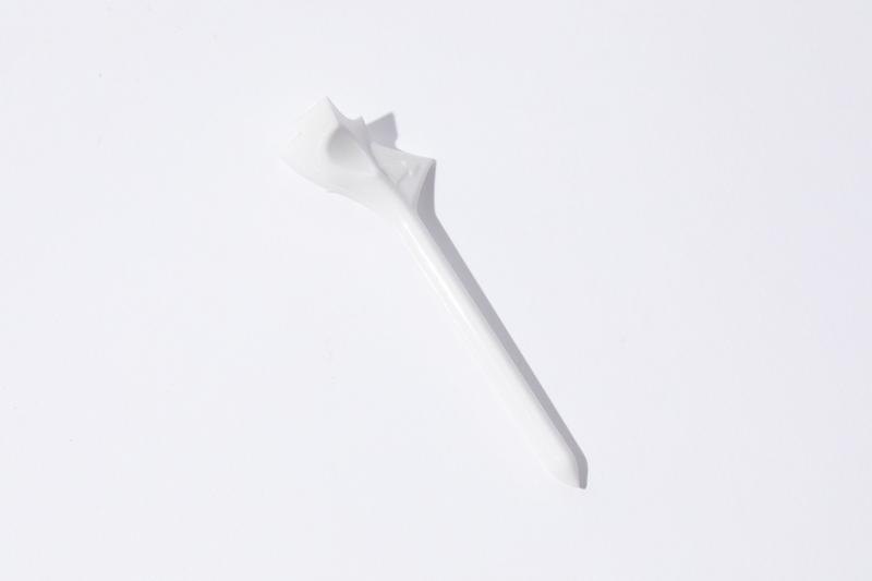 Close-up of a single white FlightPath polymer golf tee showing its low-friction head design