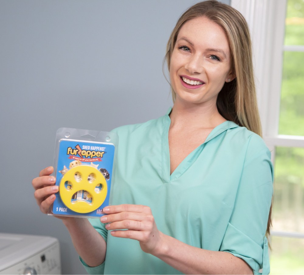 A person holding a FurZapper pet hair remover pack in a laundry room