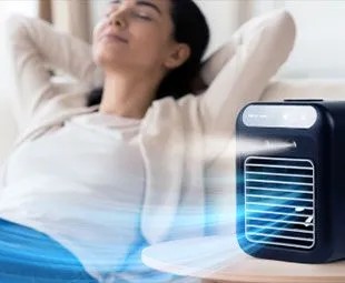 Person relaxing beside the Glacier Breeze personal cooler as it runs on a table