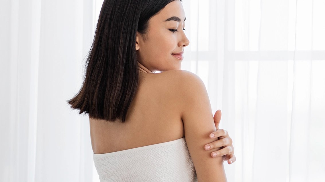 A person with smooth skin and hair in soft light after showering with the Glokore Filtered Showerhead