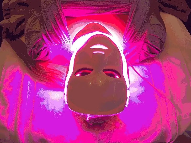 Person relaxing while wearing the Glokore LED face mask lit up