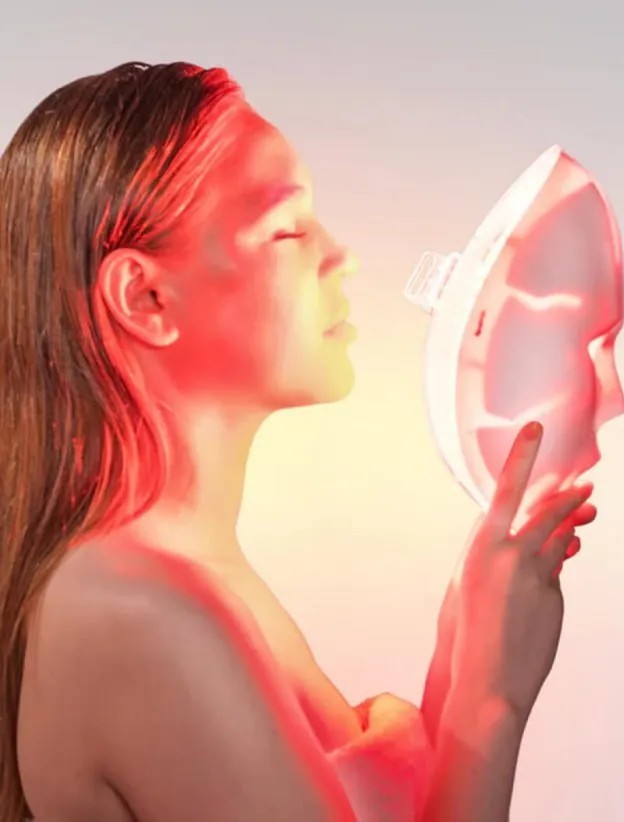 Glokore LED face mask glowing red while held up to the face