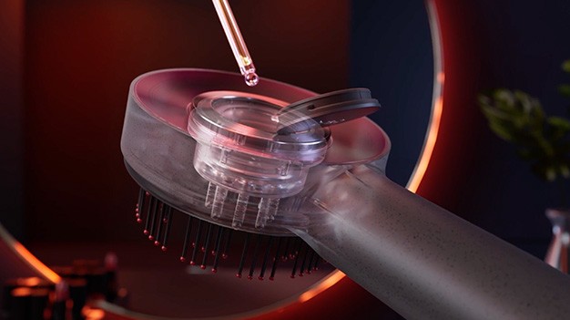 Serum being loaded into the Glokore Scalp Massager's built-in chamber before use