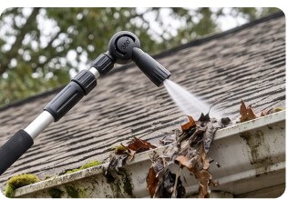 Close-up of the Gutter Hero telescopic wand's rotating spray head flushing leaves out of a clogged gutter