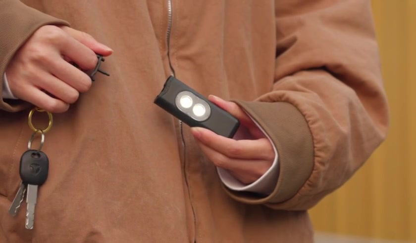 Hand pulling the activation pin on a Halo Siren personal safety alarm clipped to a set of keys