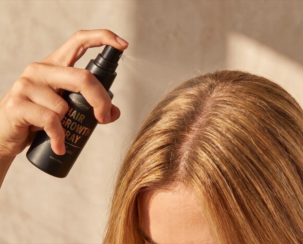 Misting the HaloGrow Hair Growth Spray onto the scalp at the hair parting
