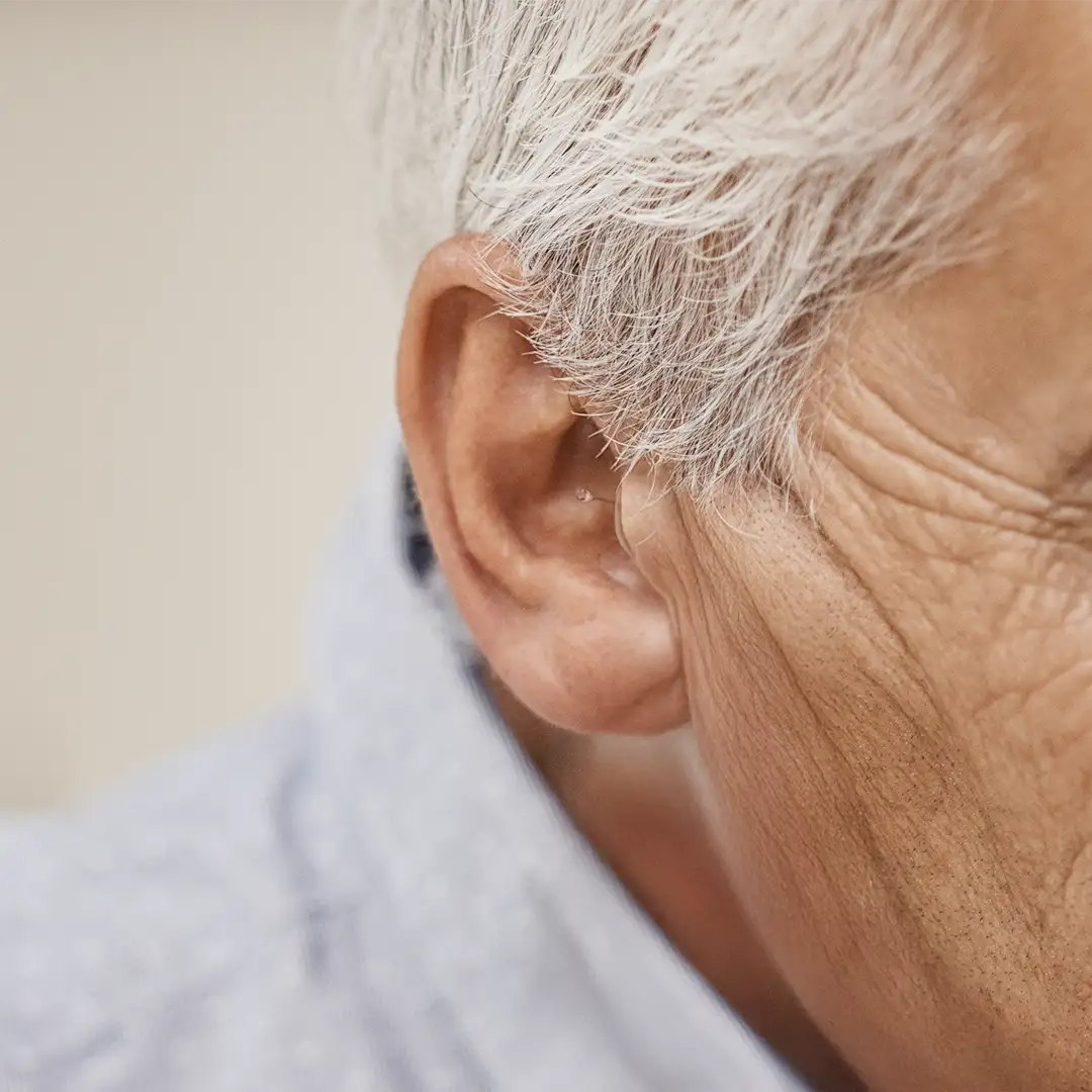 Close-up of a HearWell in-canal hearing aid worn in the ear, showing how discreet the fit is