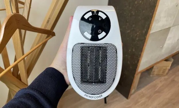 Compact HeatSpace ceramic heater held in one hand to show its palm-size footprint