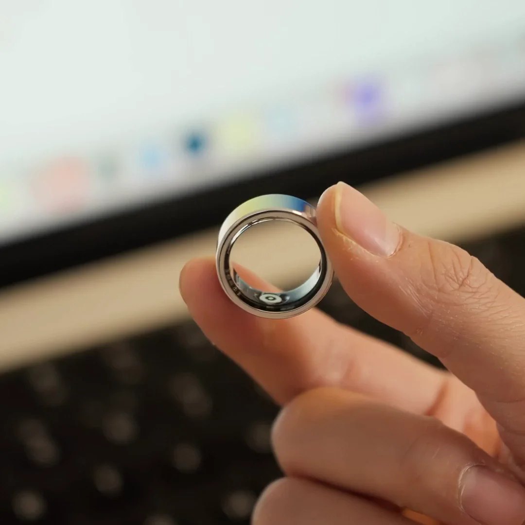 A person holding the Herz P1 Smart Ring between two fingers, showing the sensor puck inside the band