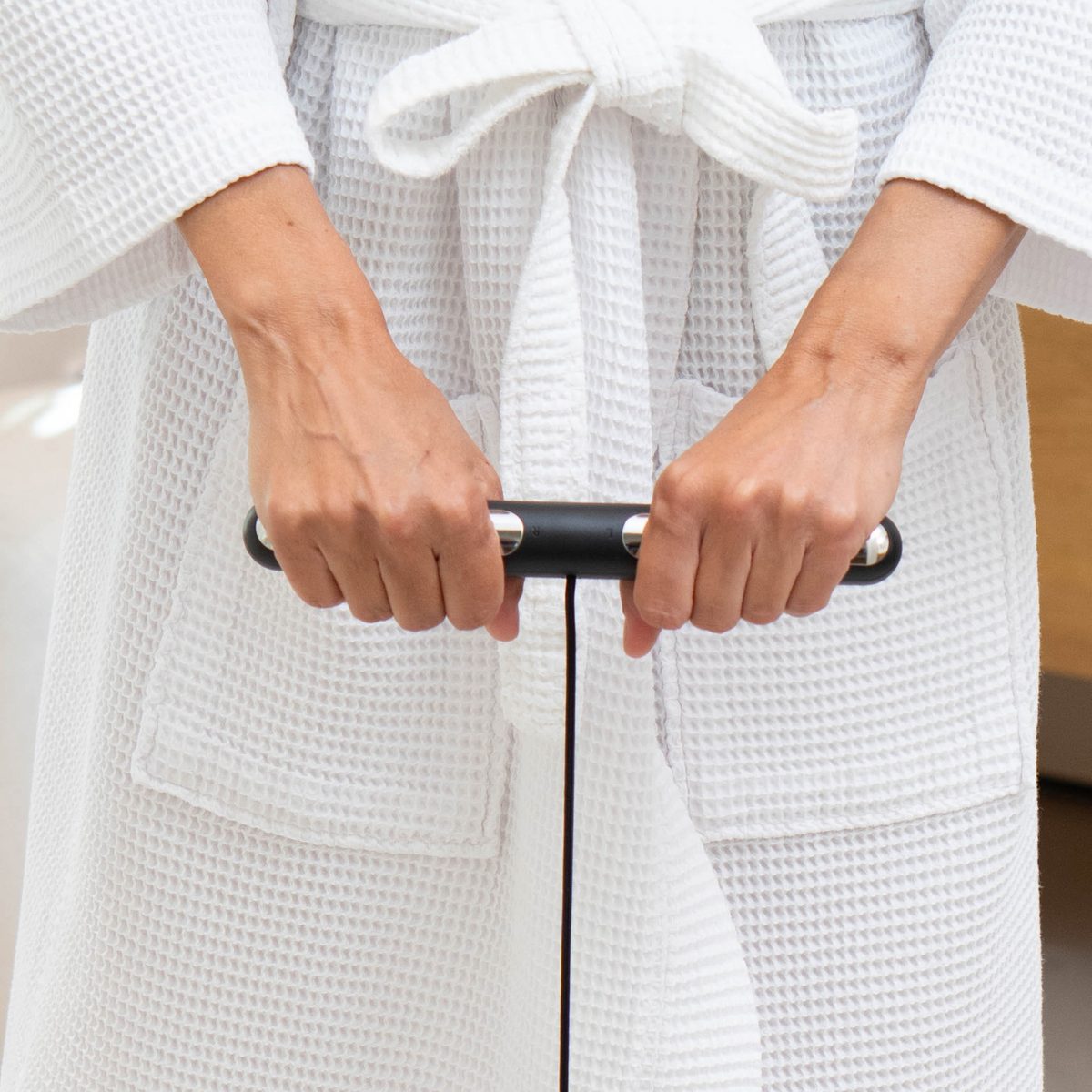 Close-up of two hands gripping the Herz P1 Smart Scale's retractable 8-electrode handle during a body-composition scan