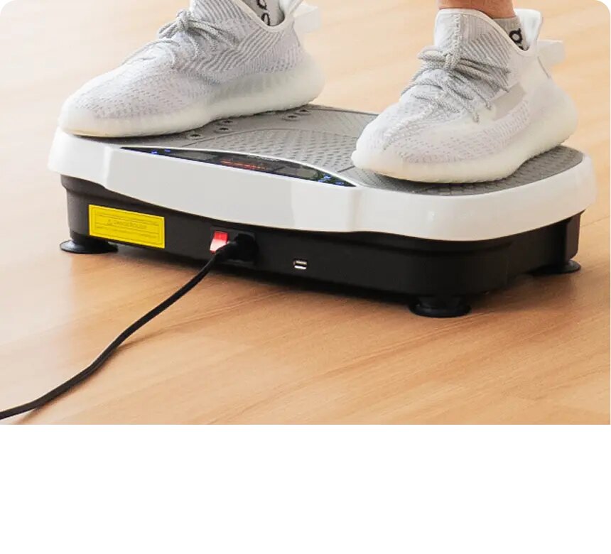 A person standing on the Herz P1 oscillating vibration plate on a wood floor
