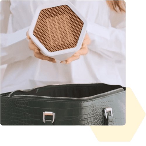 Person holding the compact hexagon-shaped HexaHeat portable ceramic heater in both hands