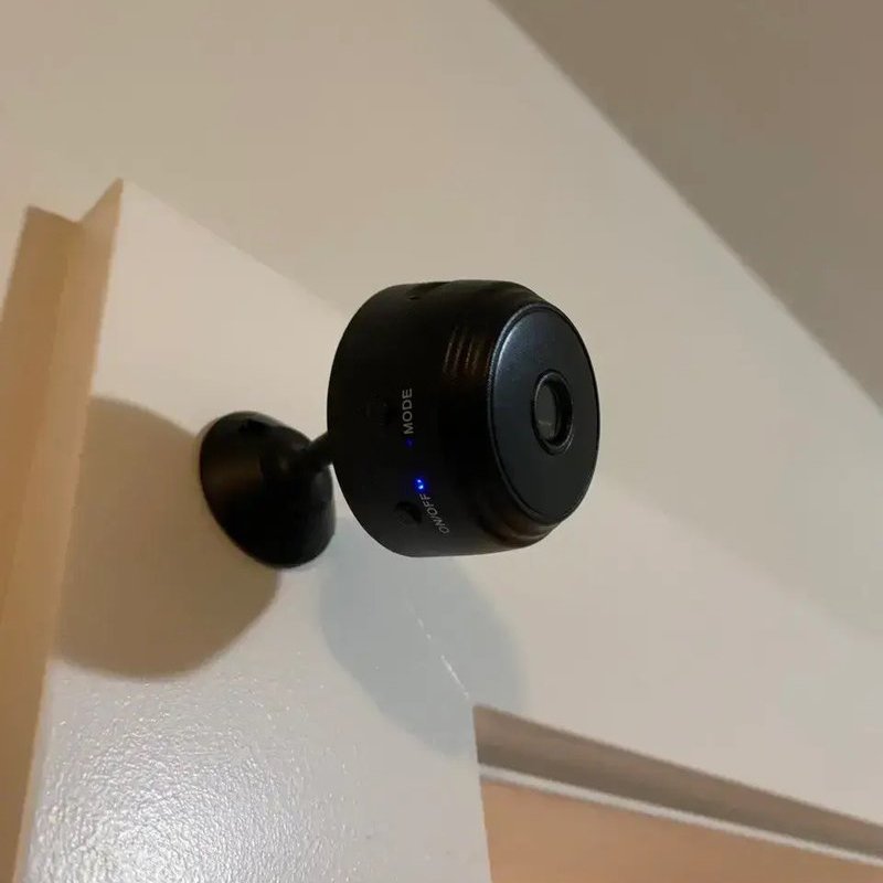Home Defender Cam mini security camera mounted high on a door frame in a customer's home