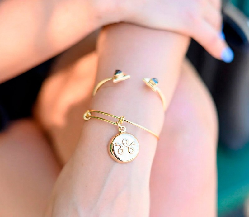 invisaWear gold bangle bracelet with a hidden panic-button charm on a woman's wrist