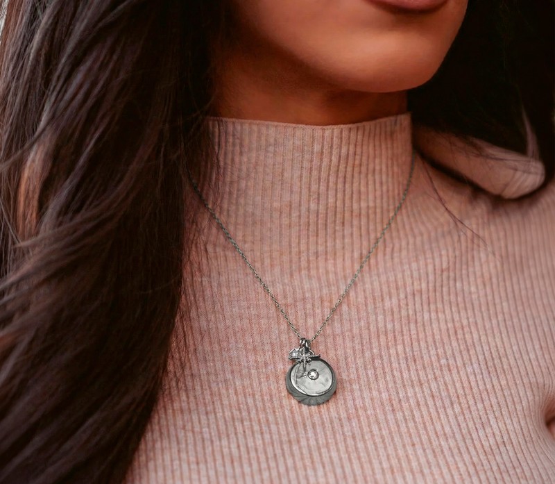 Silver invisaWear smart safety pendant necklace worn over a ribbed high-neck top
