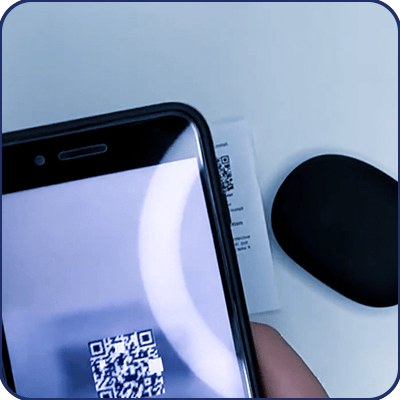 Hand holding a phone scanning the Keilini TalkEase setup QR code next to the earbuds