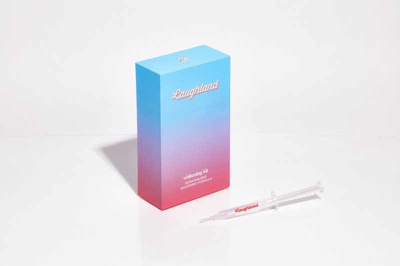 LaughLand whitening kit box next to a personalized whitening gel syringe