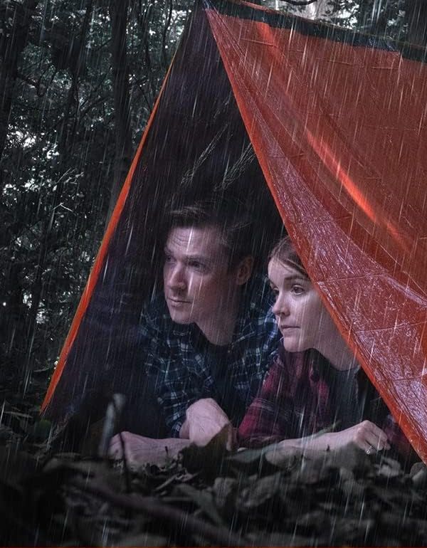 Two people sheltering under the orange LifeTent tube tent during rain in a forest