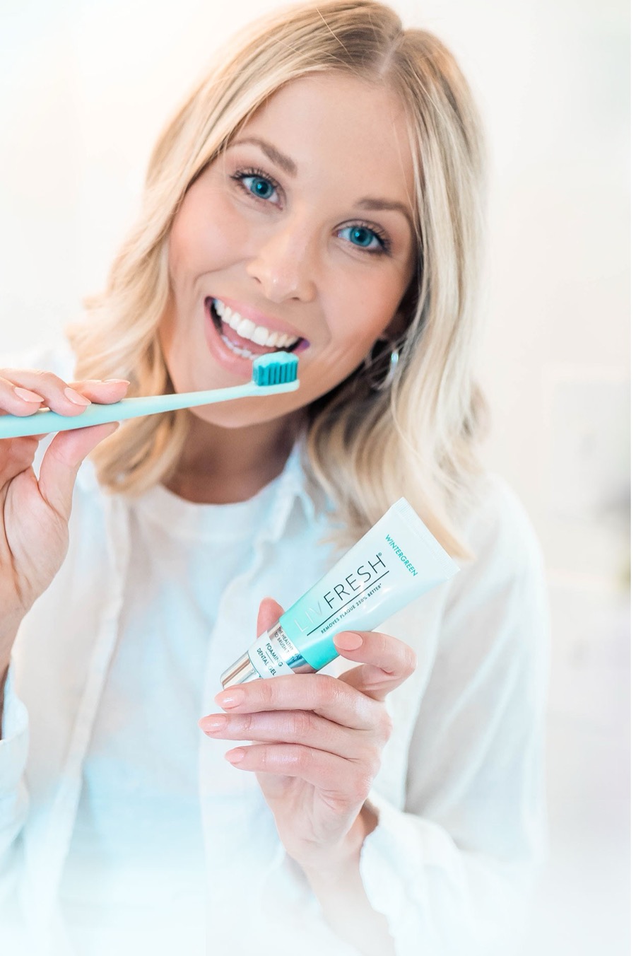 Person holding a toothbrush and a tube of LivFresh Wintergreen dental gel