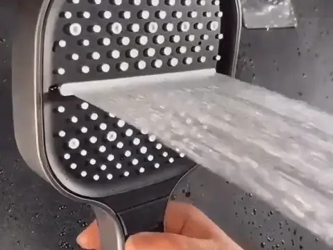 Close-up of the Loft Home Essentials showerhead spraying a high-pressure jet, held in hand