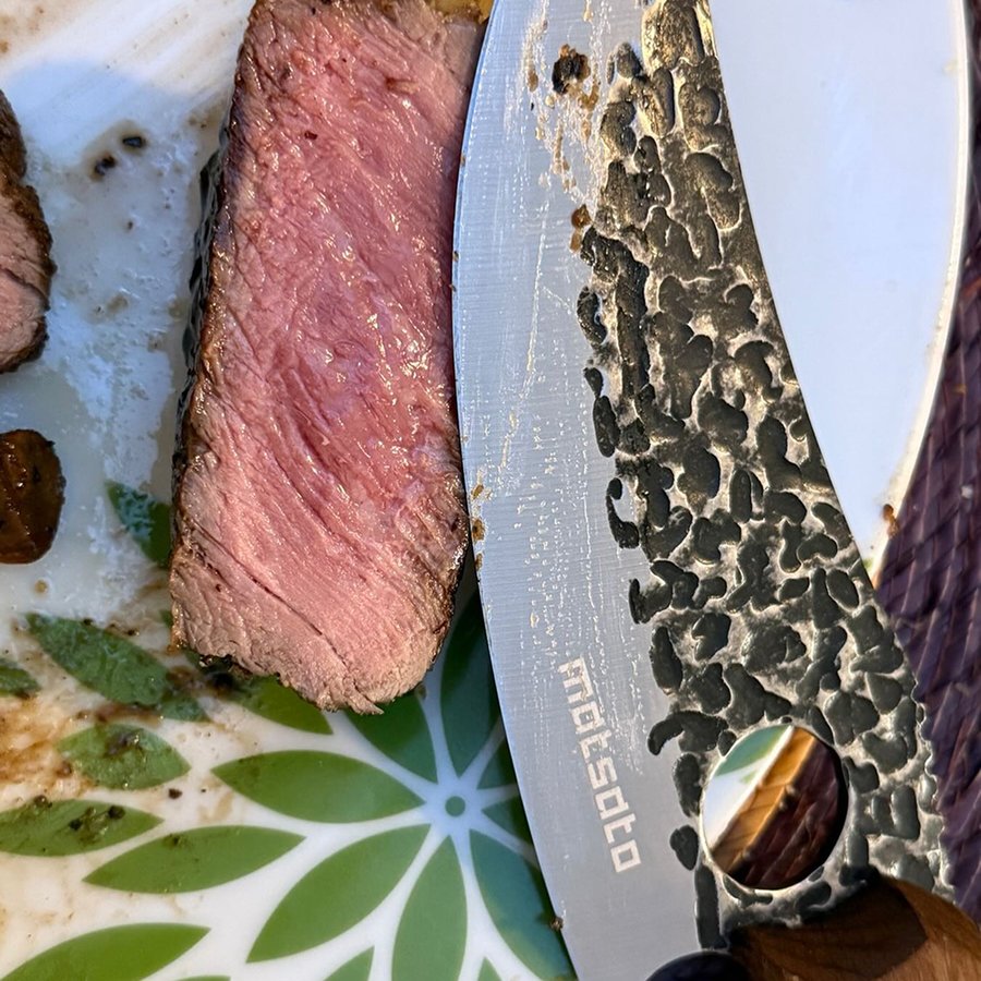 Close-up of the hammered Matsato blade beside a sliced medium-rare steak