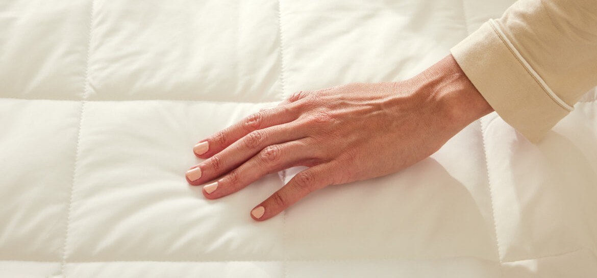 Close-up of a hand pressing the quilted texture of the Miracle Made Cooling Comforter