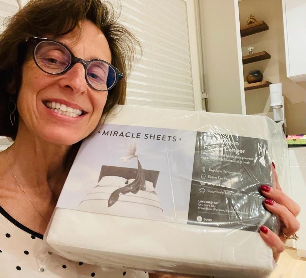 Smiling customer holding a new packaged set of Miracle Sheets